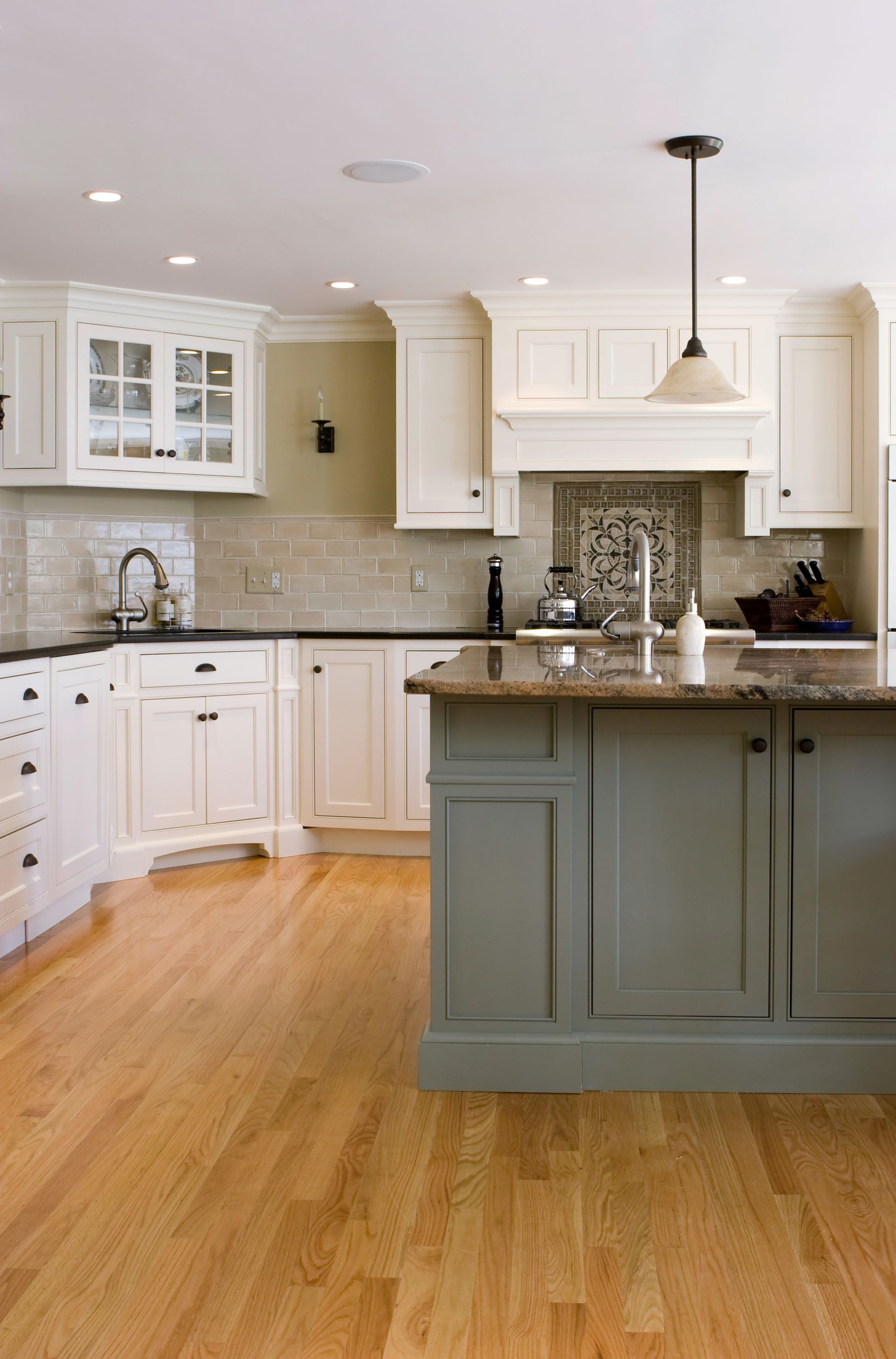 Kitchen with white cabinets, wood floors, and a gray island.
