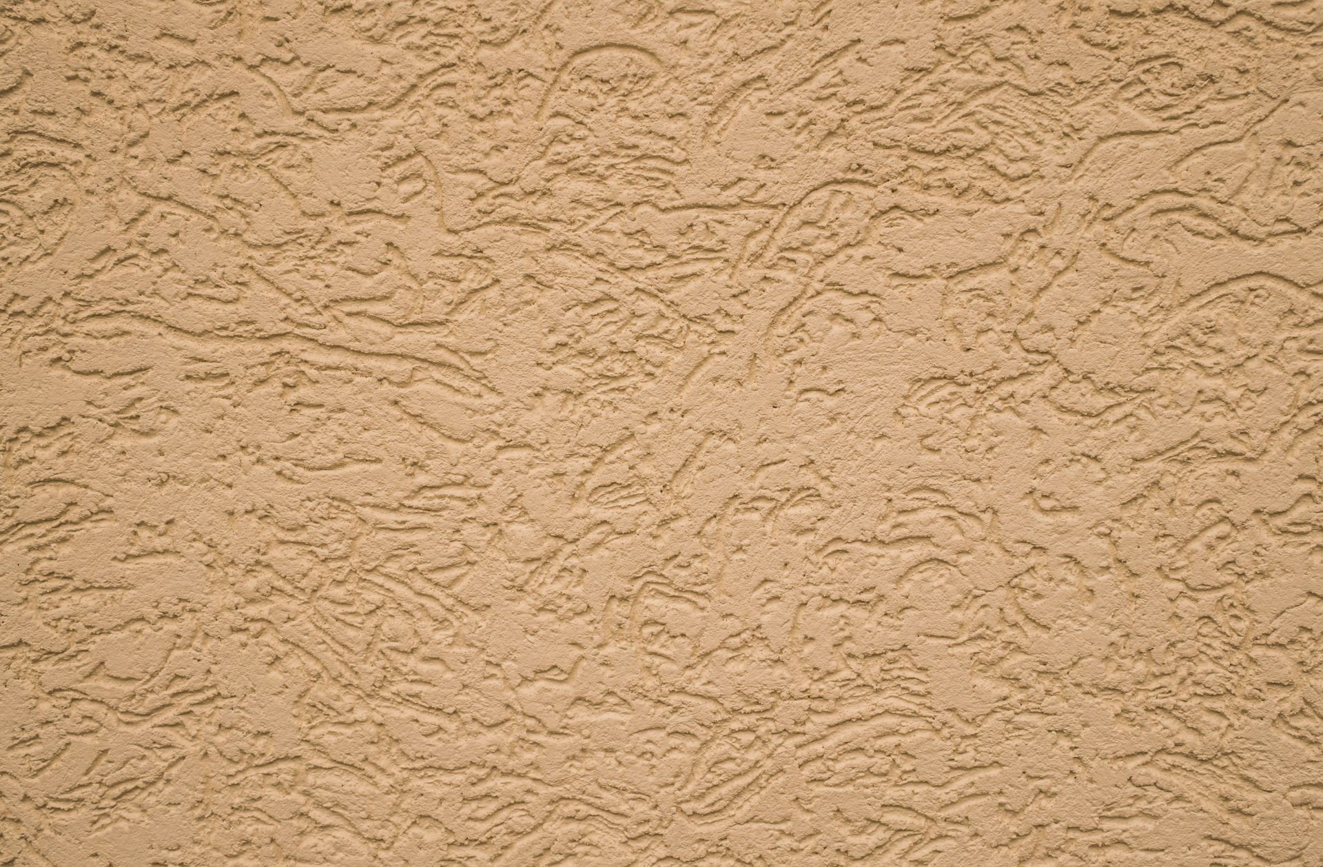 Tan stucco wall with textured, rough surface.