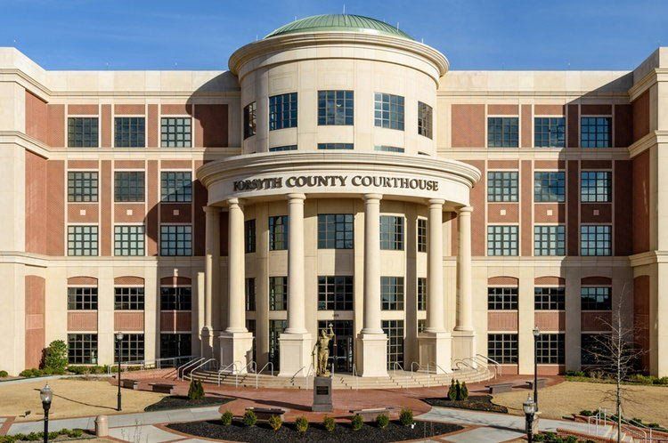 Forsyth County Courthouse, tan building with columns, statue, and green dome.