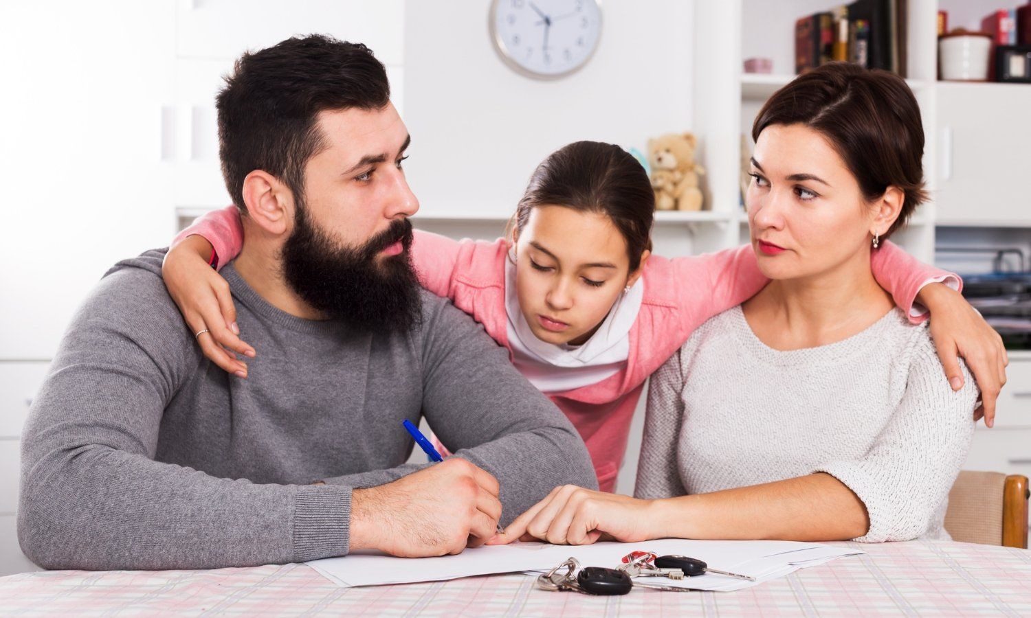 Family at table with a document. The daughter has her arms around both parents.
