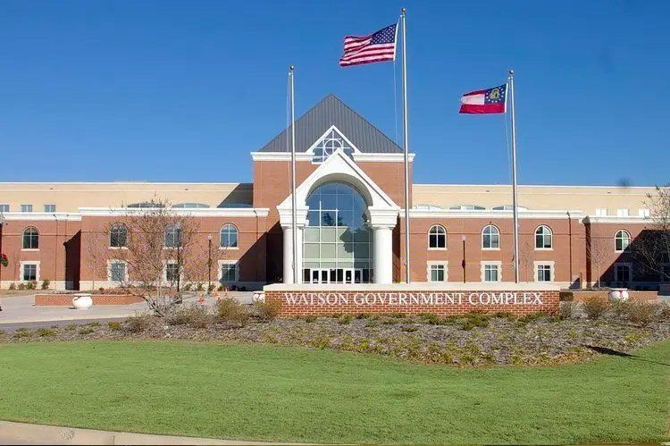 Winston Government Complex building with American and Georgia flags, blue sky.