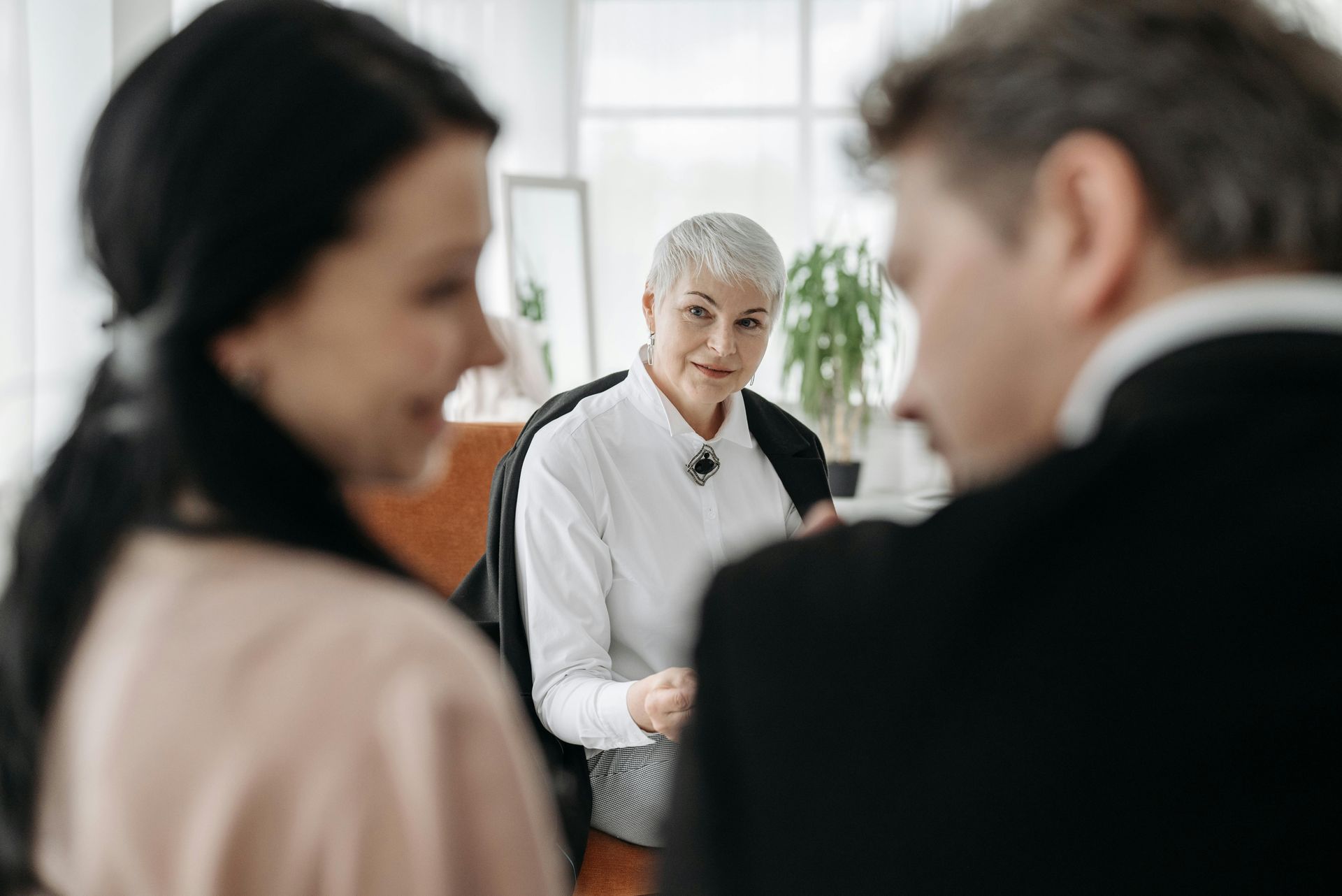 Couple in marriage counseling with a therapist, indoor setting, soft lighting.