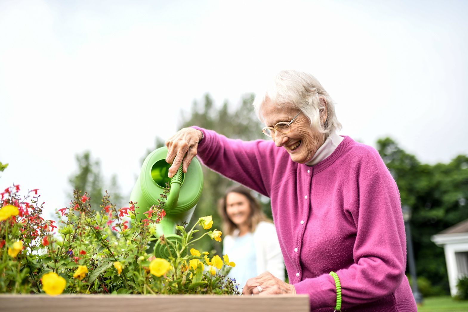 Elderly woman gardening outdoors with caregiver at Bellamy Assisted Living