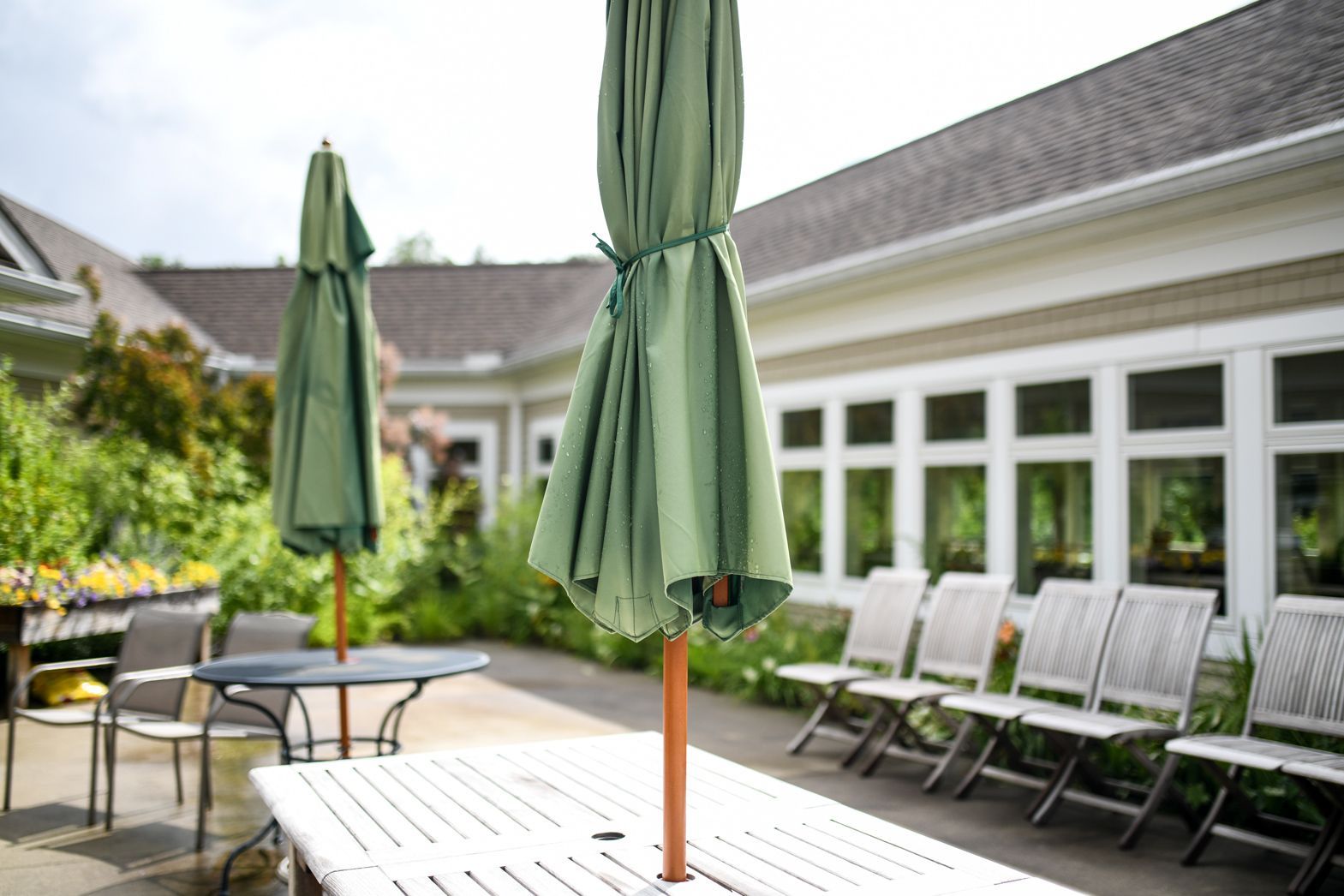 Outdoor patio seating with green umbrellas at Bellamy Assisted Living