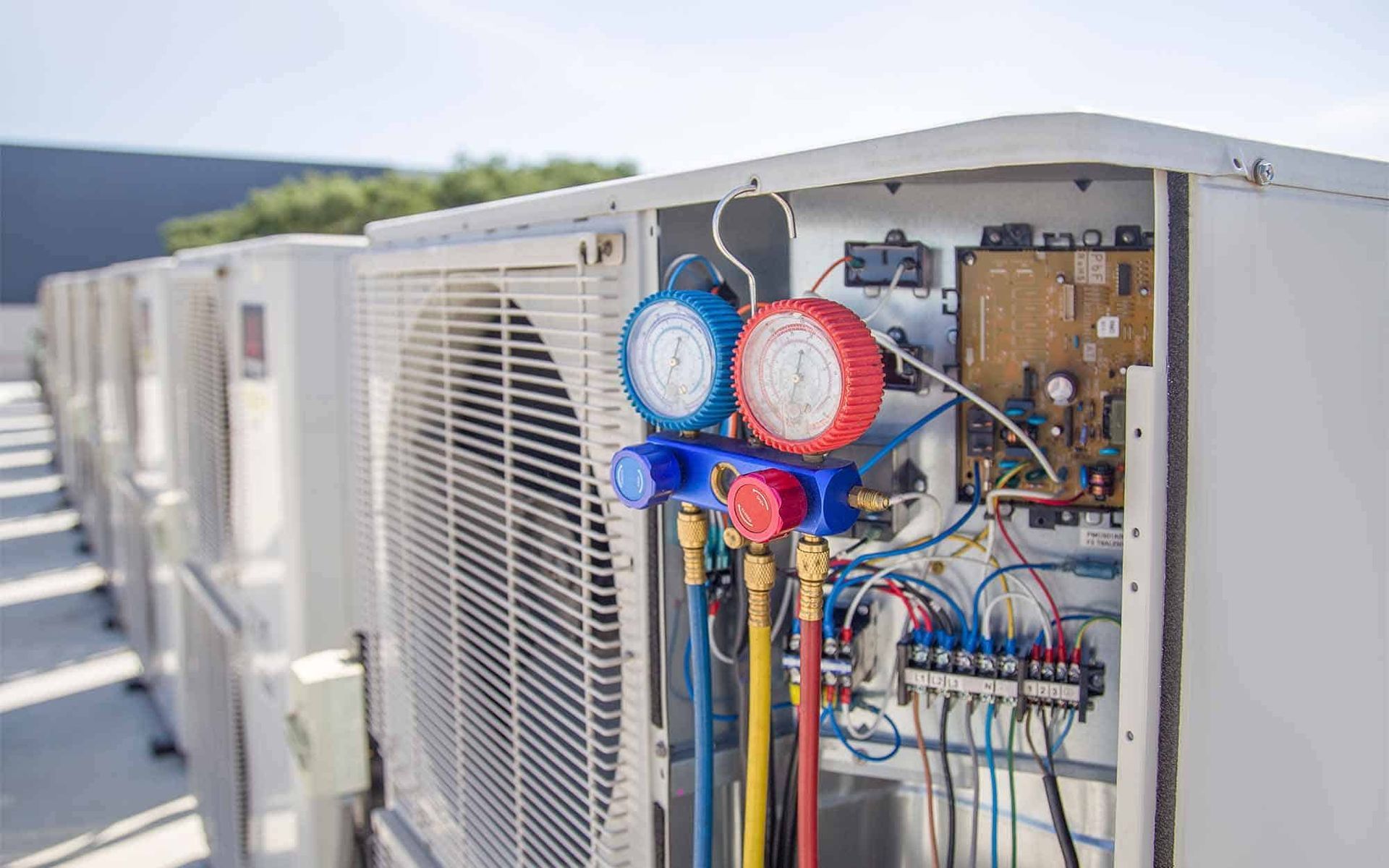 A row of air conditioners are sitting on top of a roof.