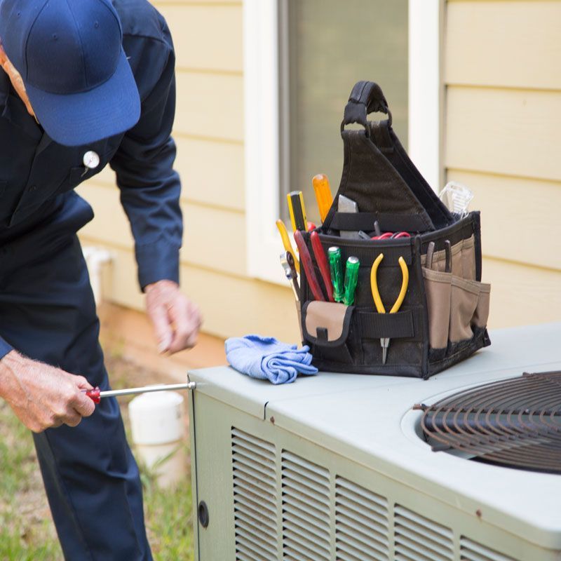 A man in a blue hat is working on an air conditioner
