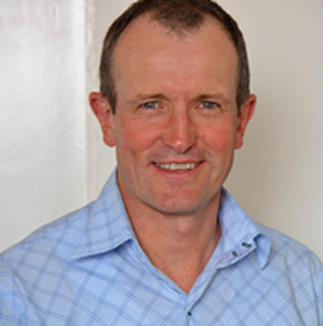 A man in a blue shirt is smiling for the camera