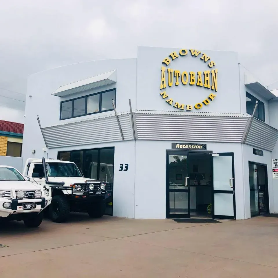 Exterior of a white building with a reception entrance and vehicles parked outside.