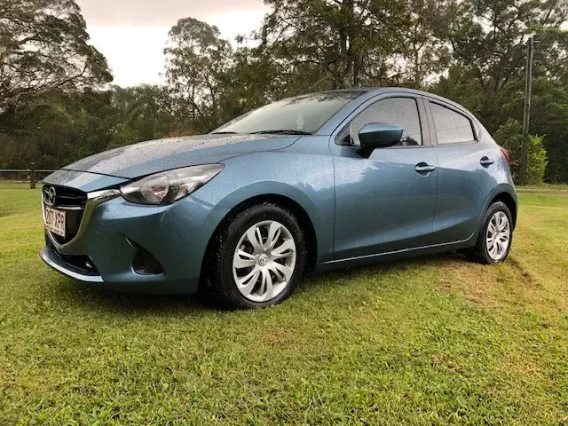 Blue Mazda 2 Parked On A Grassy Lawn