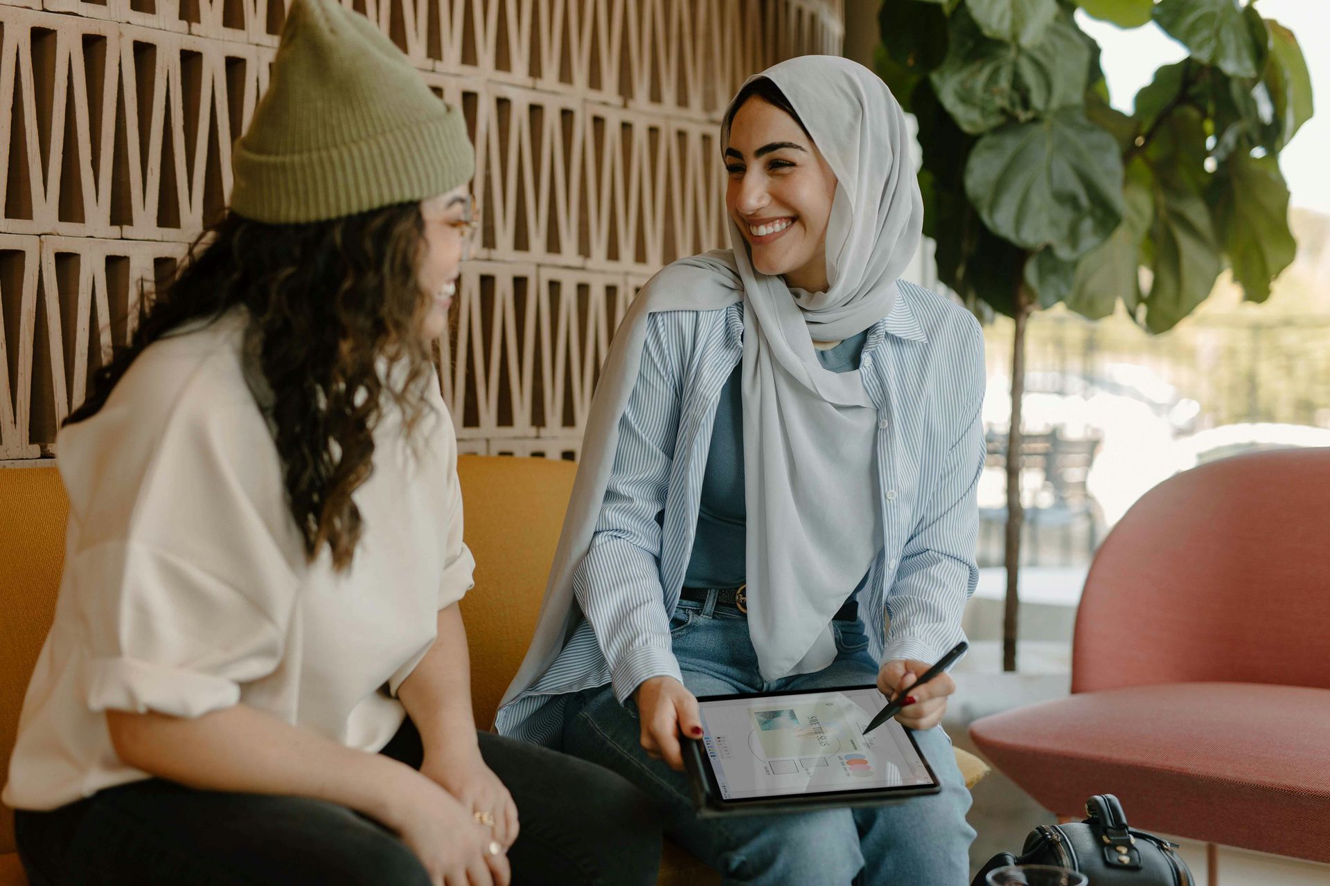 Two women are sitting on a couch talking to each other.