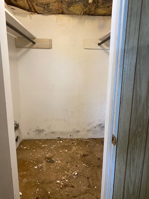 Empty closet with white walls, bare wooden floor, and shelving on both sides.