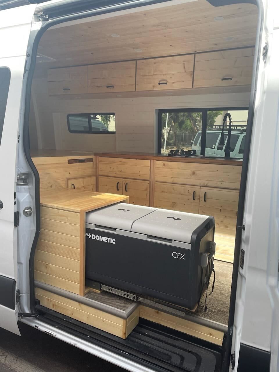 A white van with the door open and a cooler in the back.