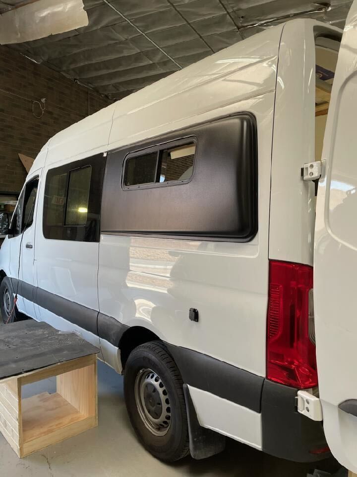 A white van with a red tail light is parked in a garage.
