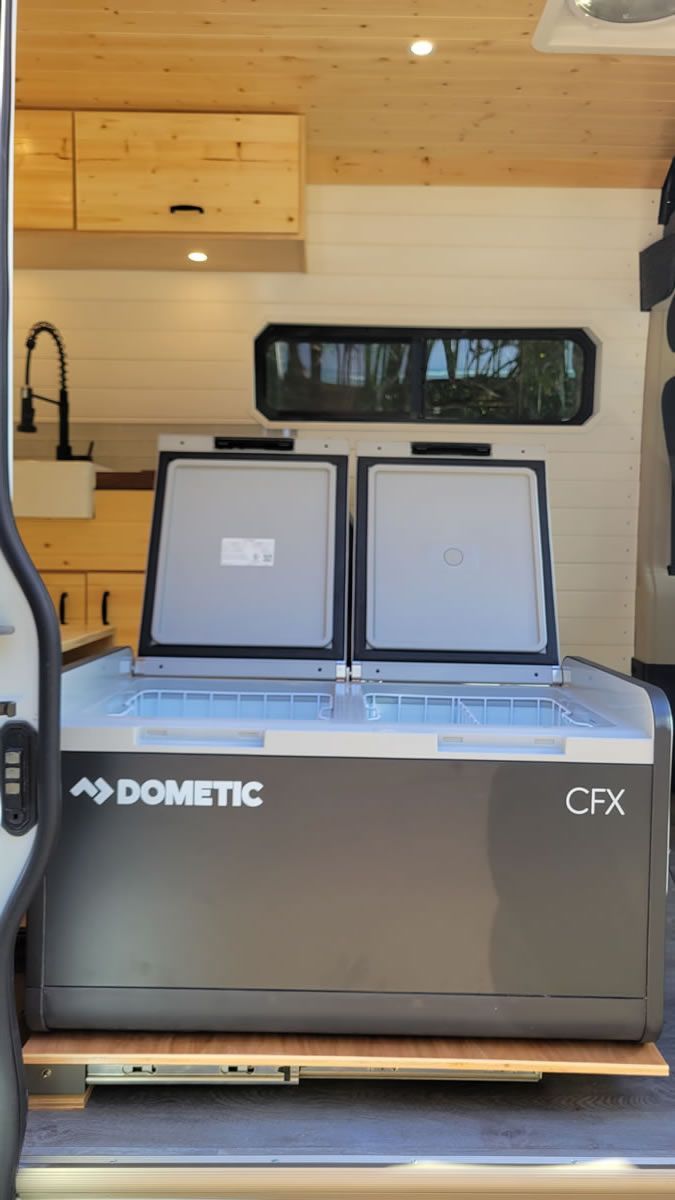 A dometic cooler is sitting in the back of a van.
