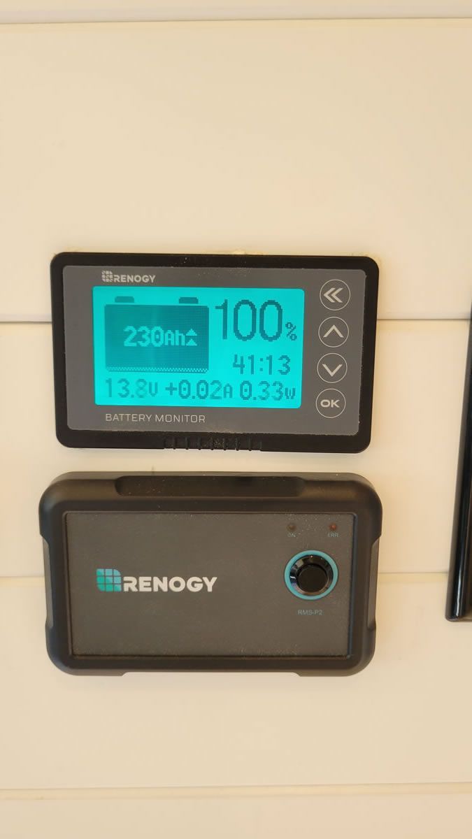 A remote control is sitting on a wall next to a cell phone.