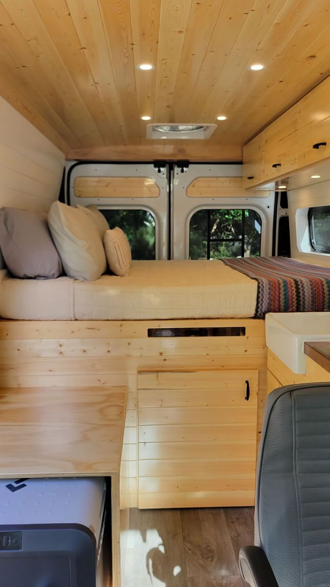 The inside of a van with a bed and a wooden floor.