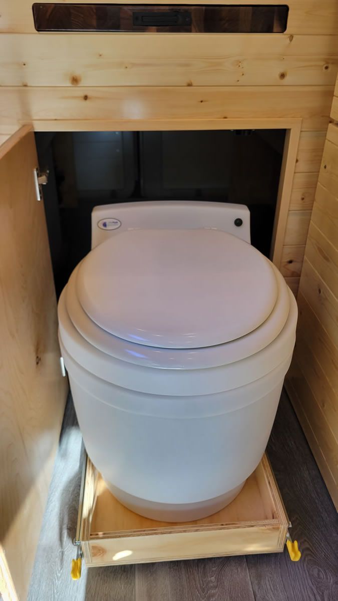 A toilet is sitting on top of a wooden platform in a bathroom.