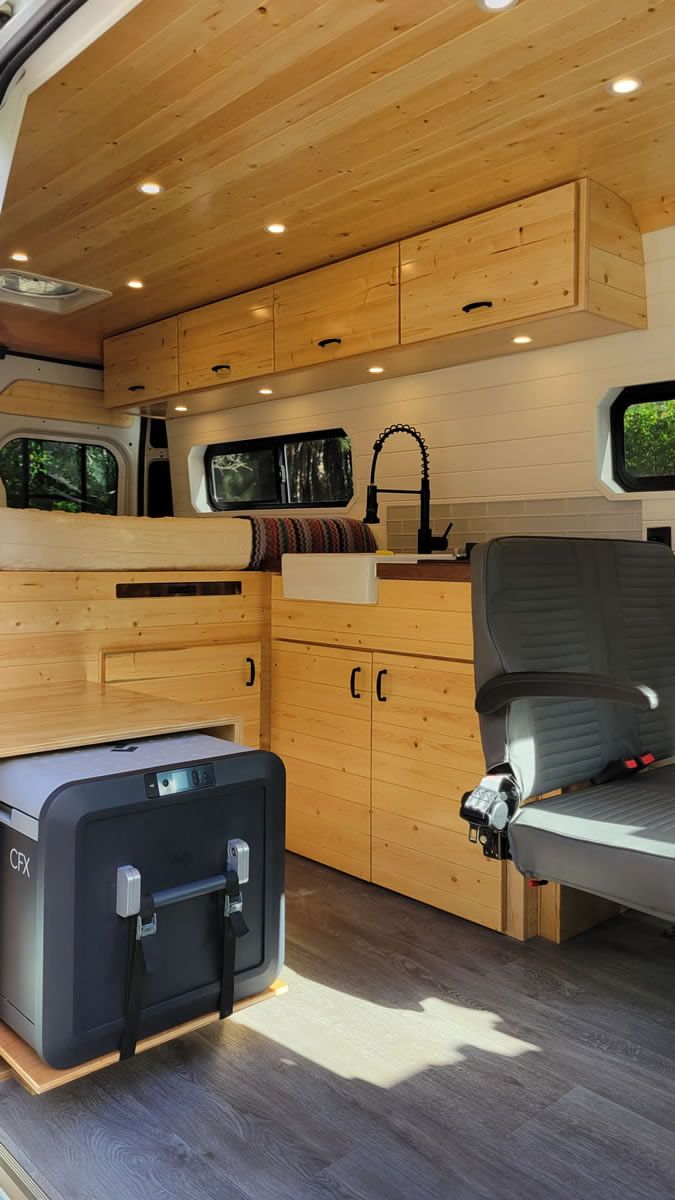 The inside of a van with wooden cabinets and a sink.