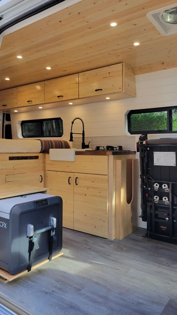 The inside of a van with wooden cabinets and a sink.