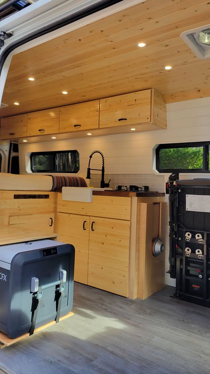 The inside of a camper van with wooden cabinets and a sink.