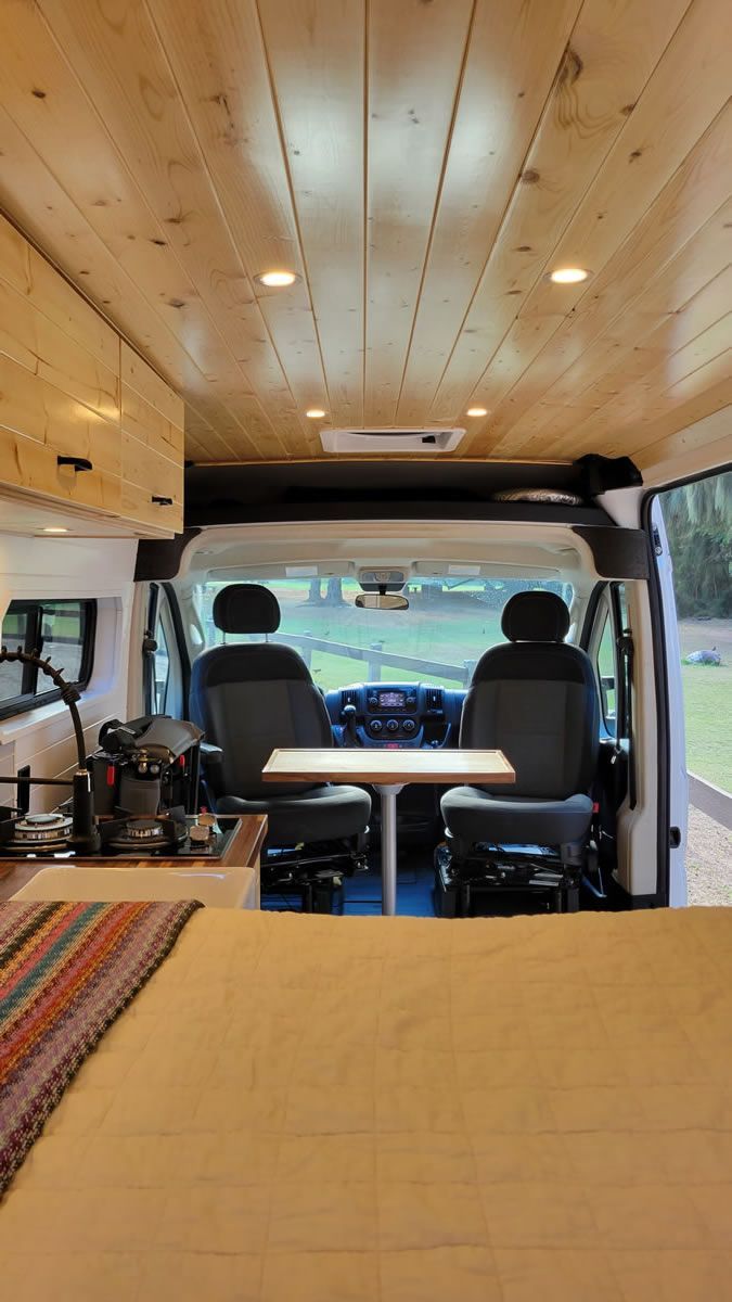 The inside of a camper van with a table and chairs.