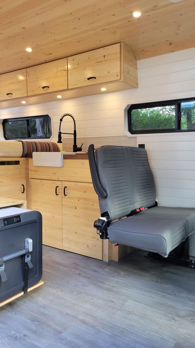 The inside of a camper van with a kitchen and two seats.