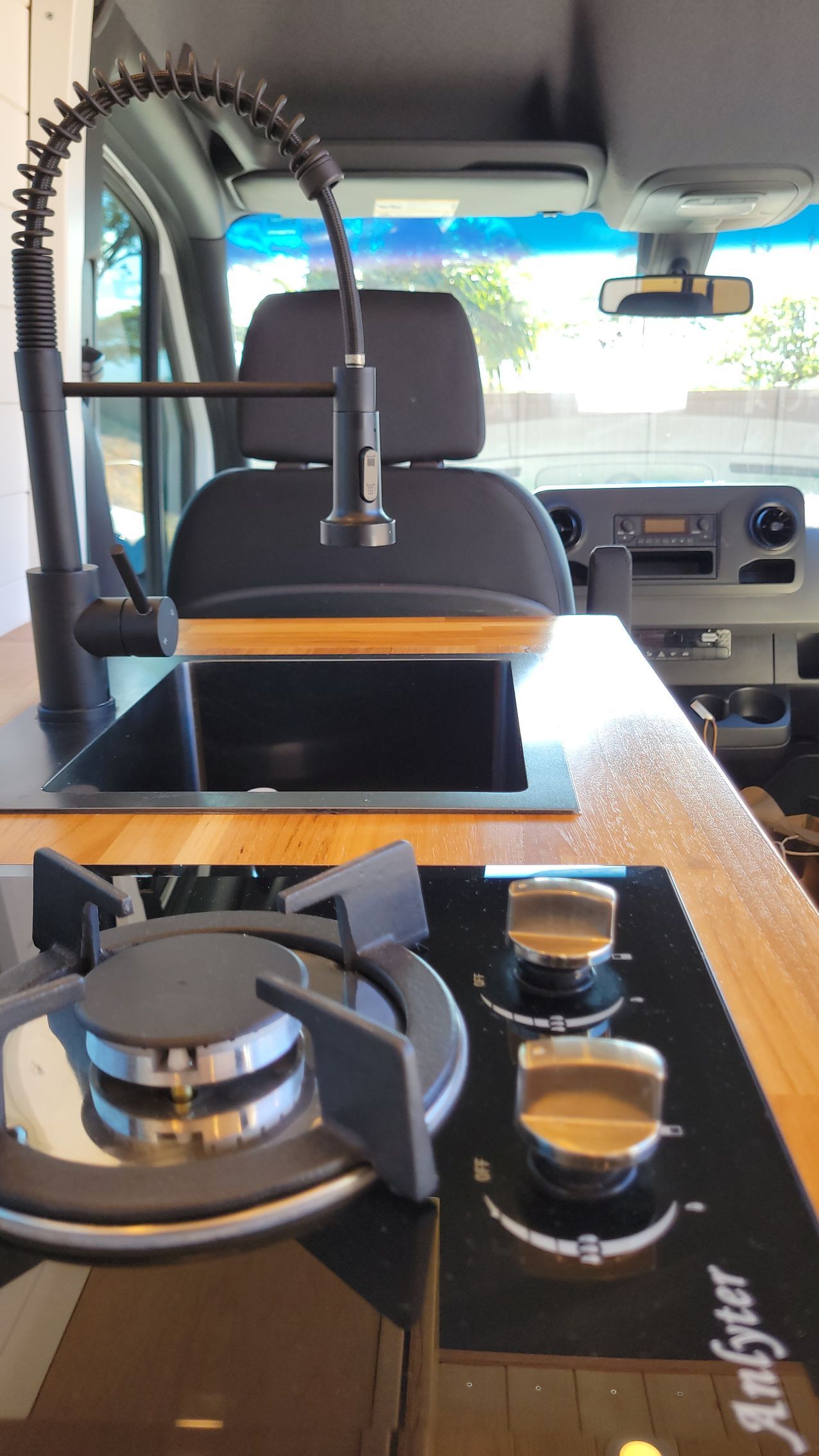 A kitchen in a van with a stove top oven and a sink.