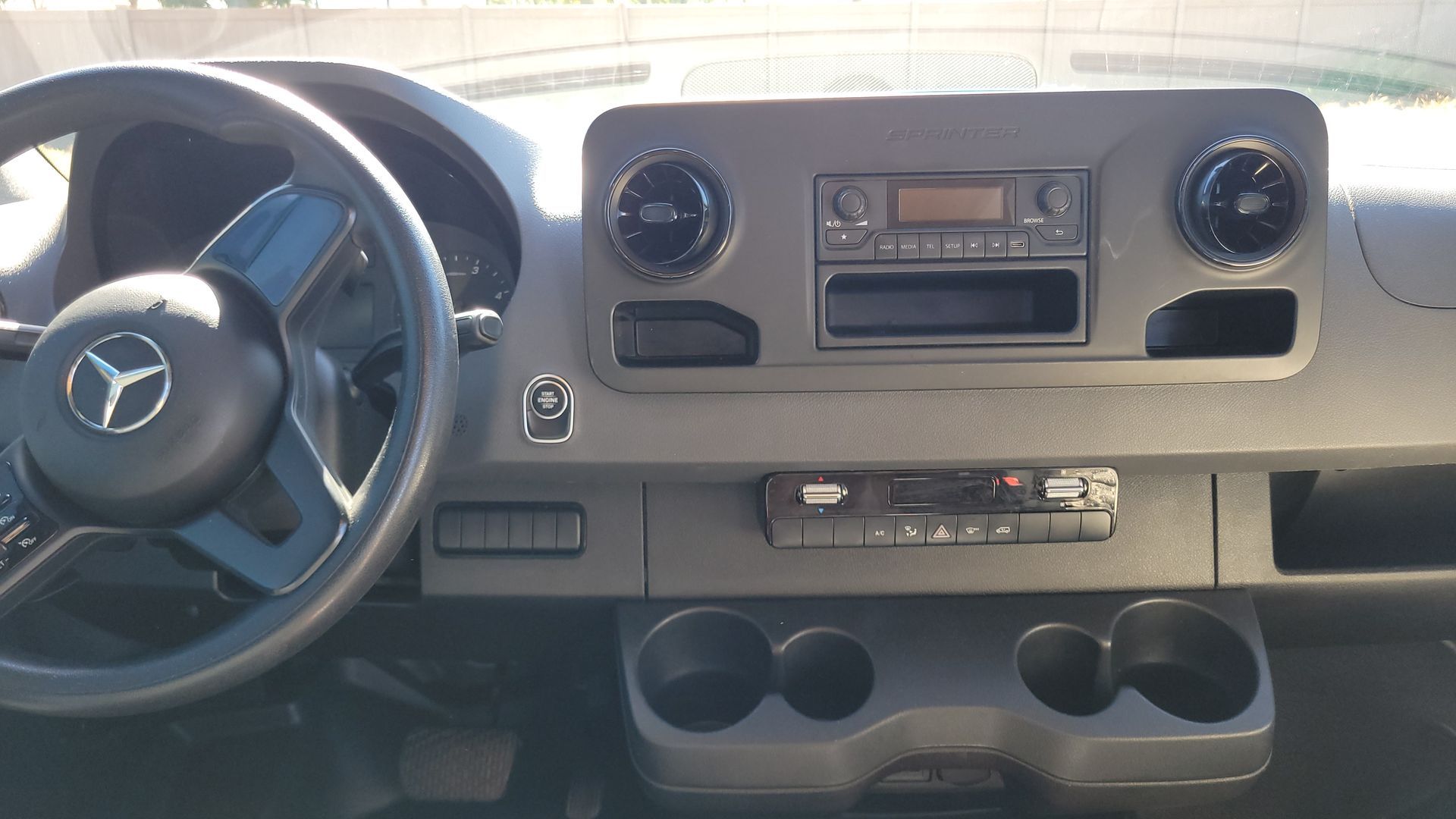 The interior of a mercedes benz van with a steering wheel and cup holders.