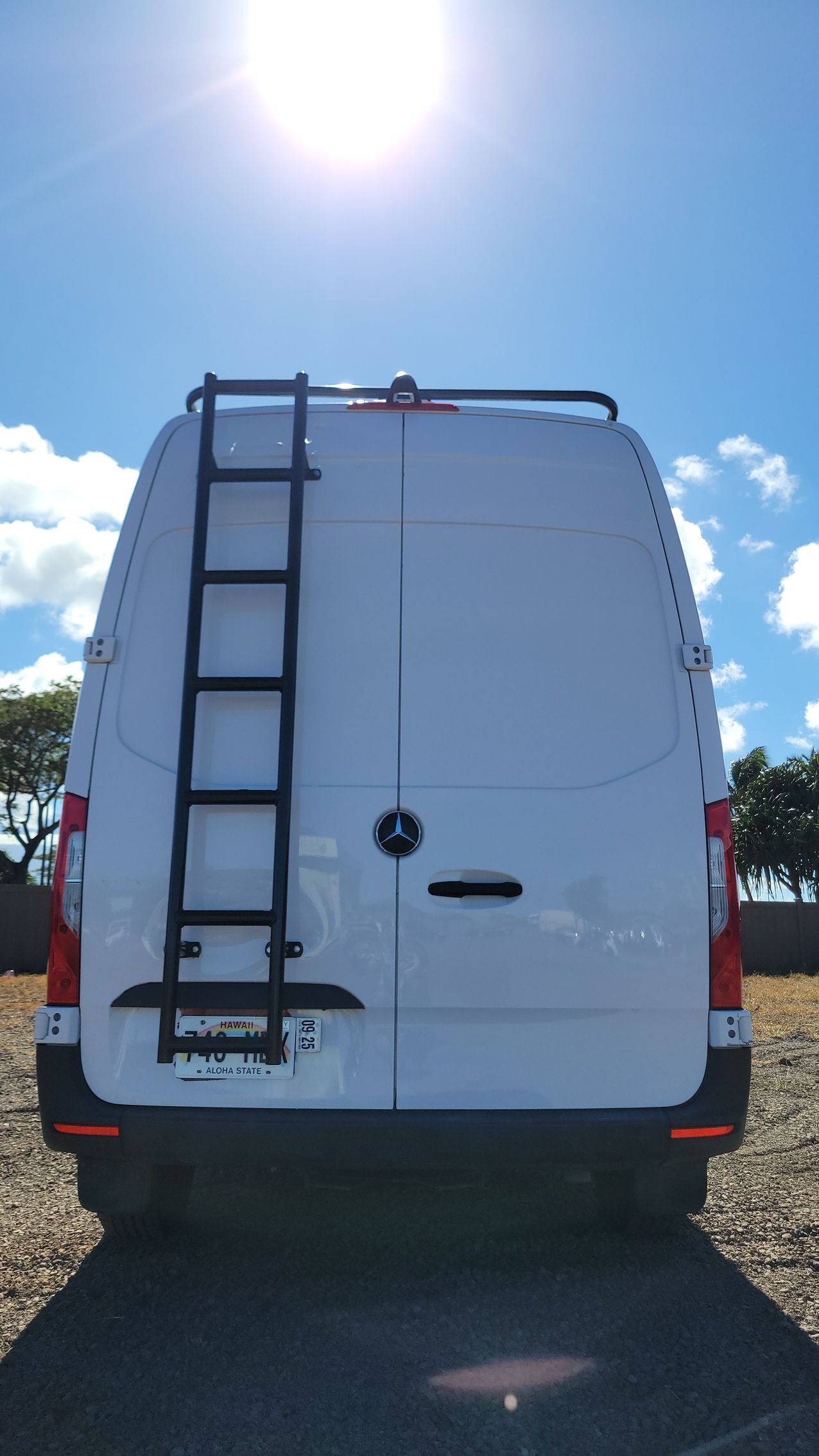 A white van with a ladder attached to the back