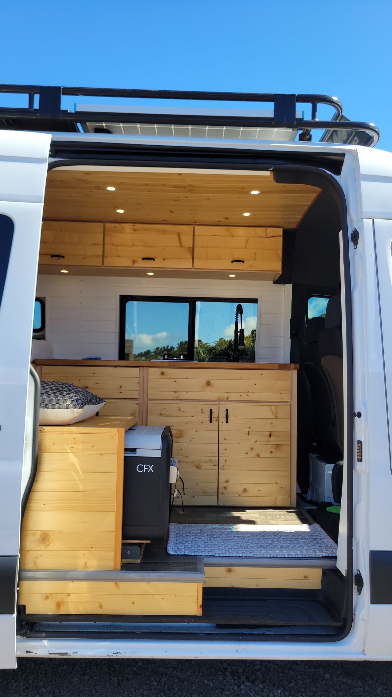 The inside of a van with the door open and wooden cabinets.