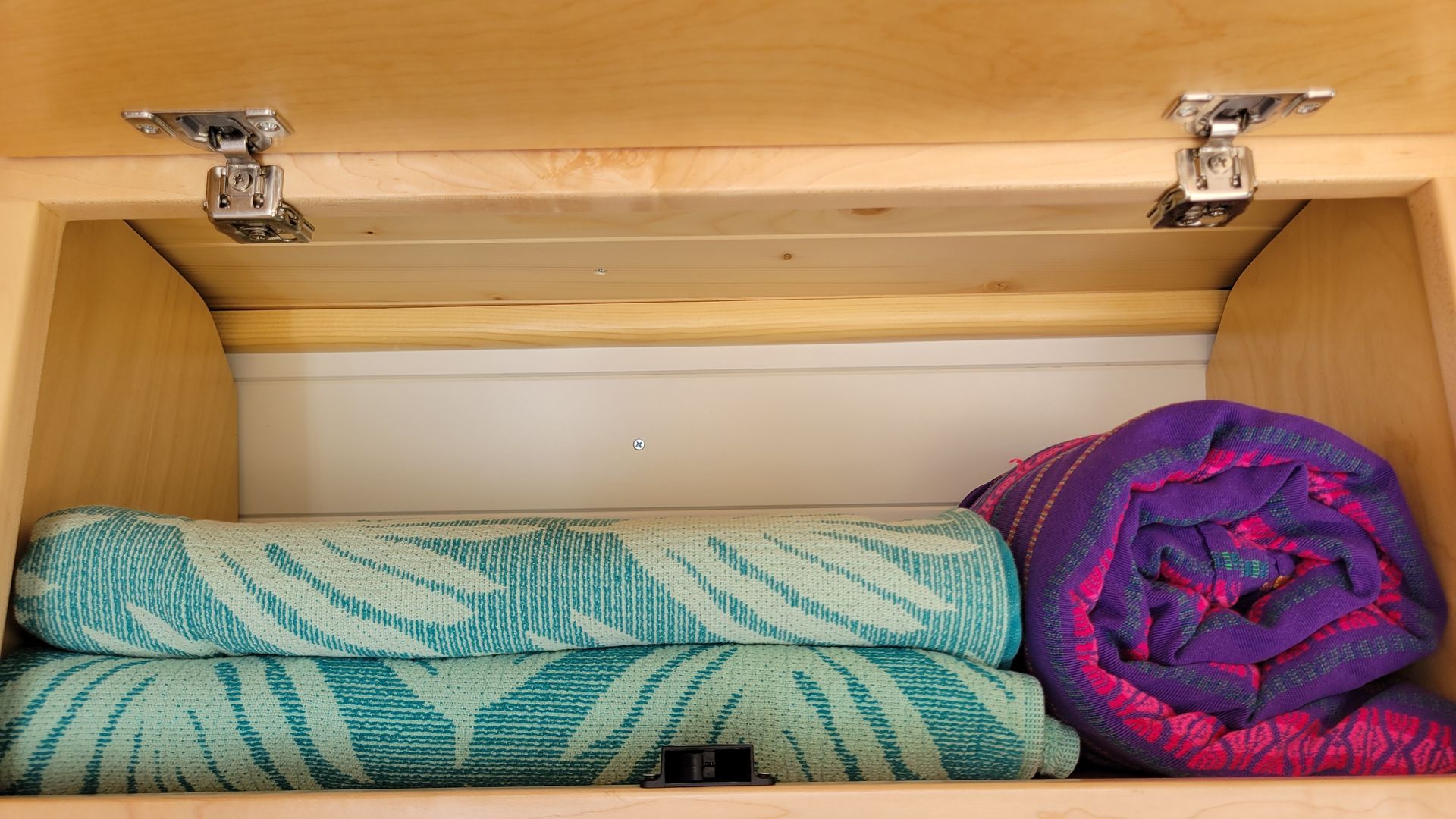 Two towels are stacked on top of each other in a wooden shelf.