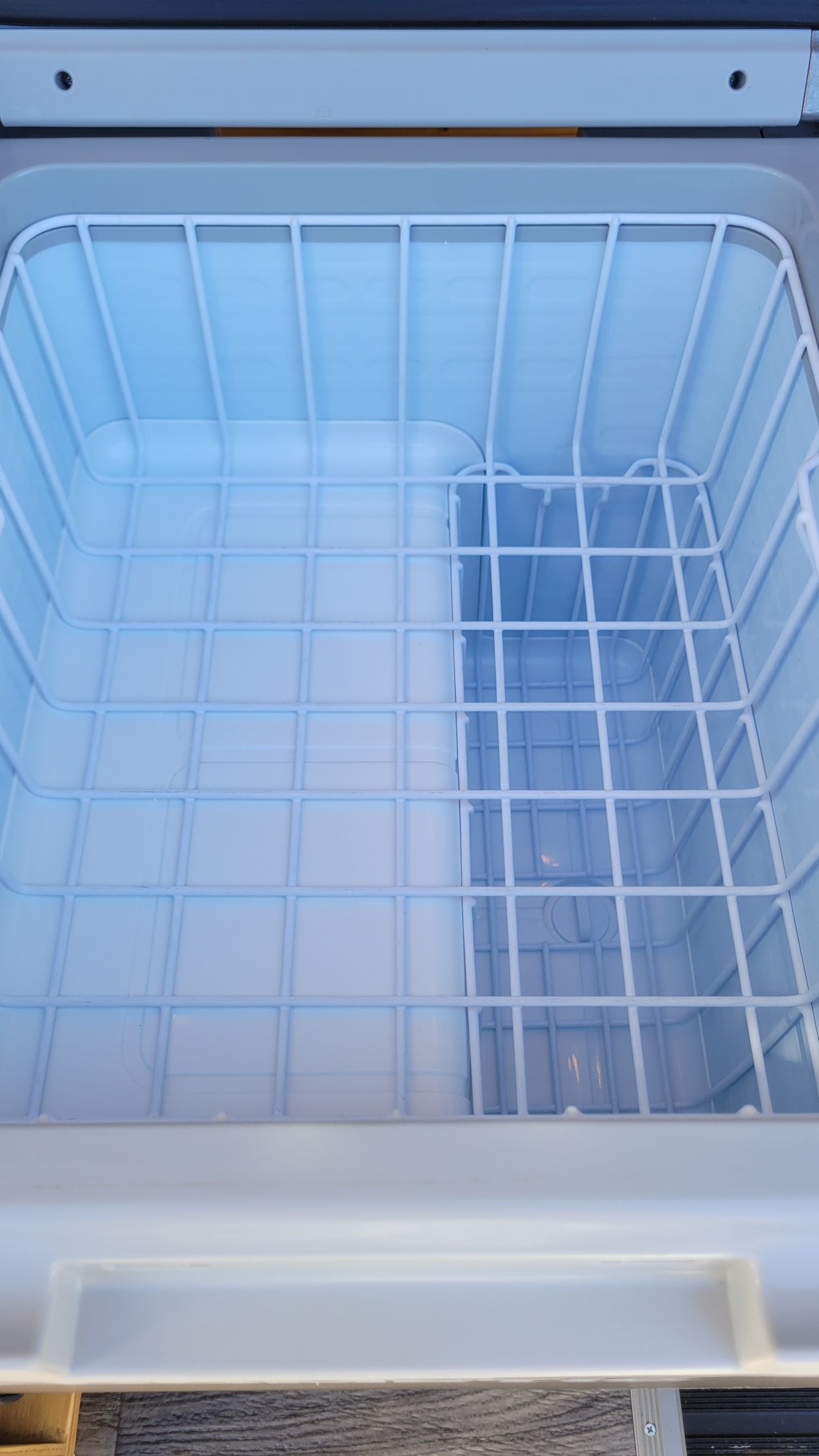 The inside of a cooler with a wire basket on top of it.