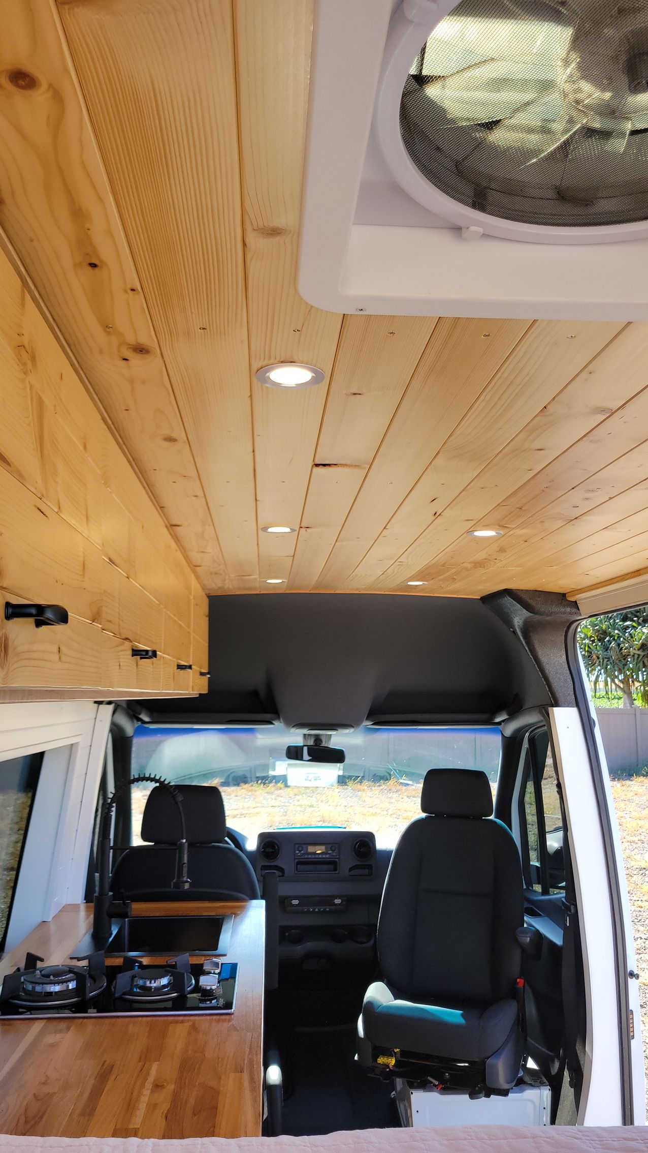 The inside of a van with a wooden ceiling and a fan.