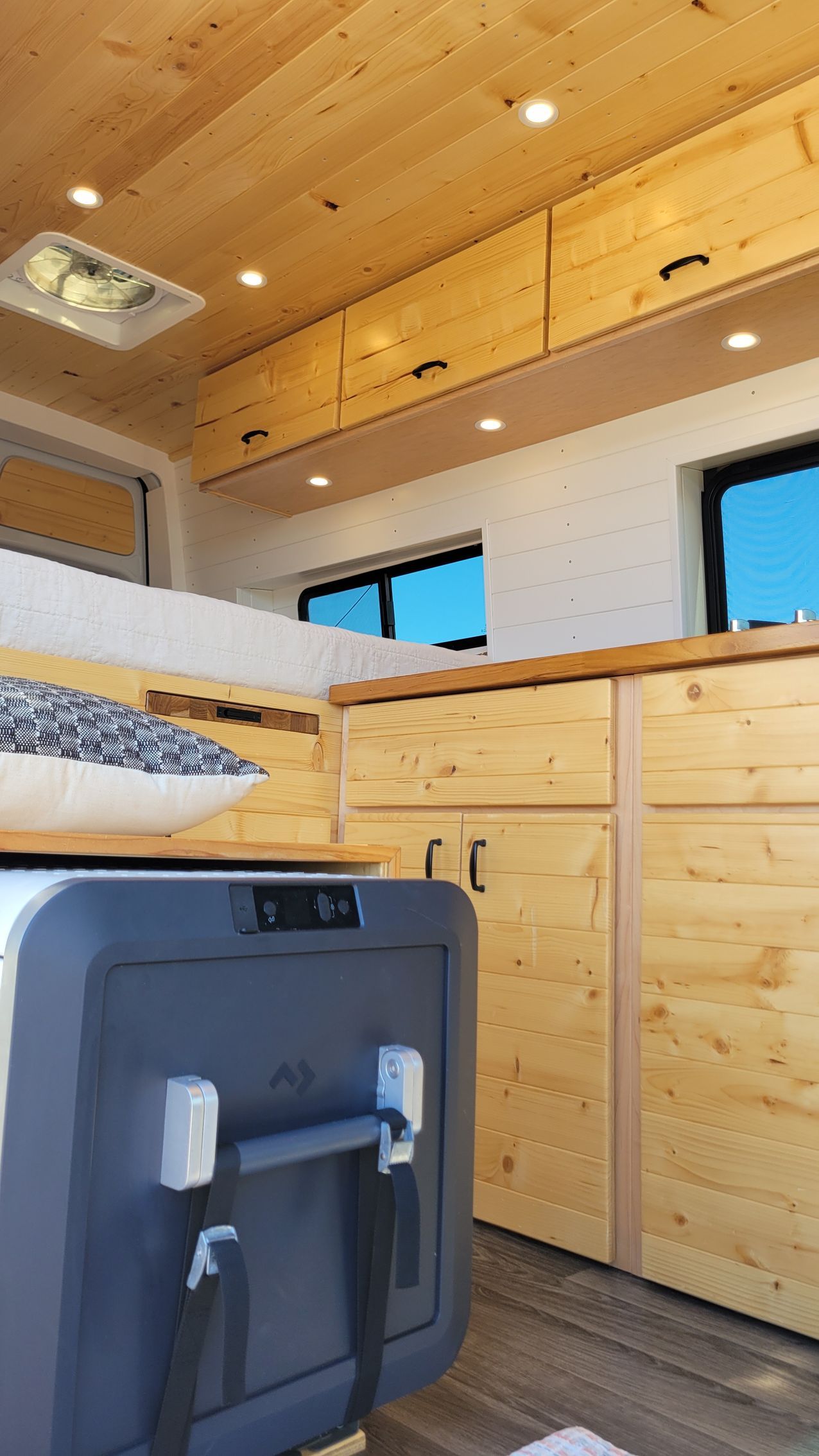 The inside of a camper van with wooden cabinets and drawers.