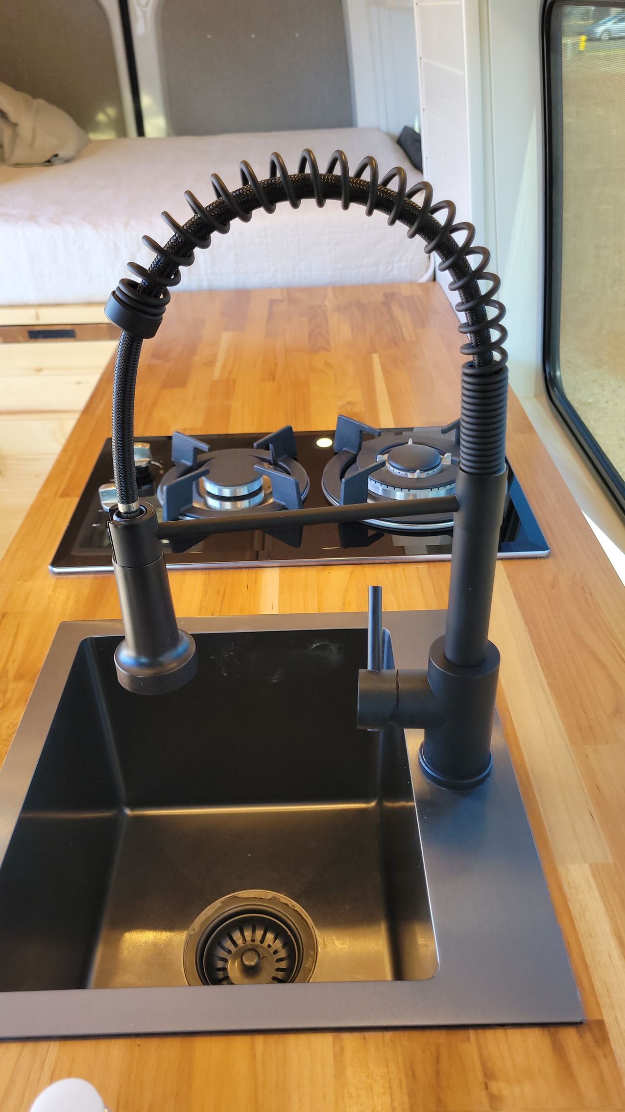A kitchen sink with a black faucet on a wooden counter top