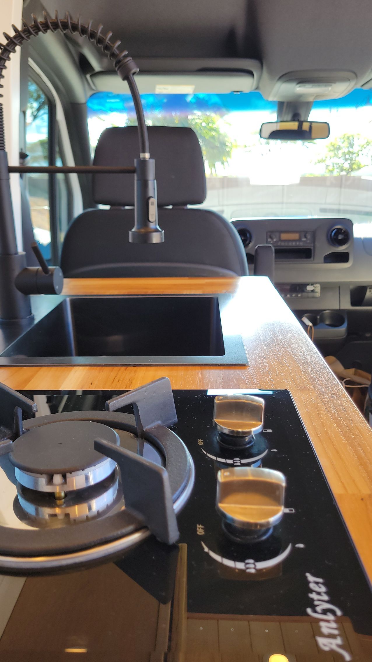A stove top oven and sink in the back of a van.