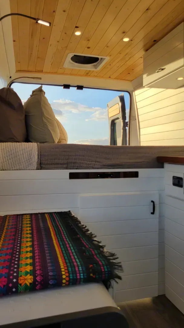 The inside of a van with a bed and a blanket on the floor.