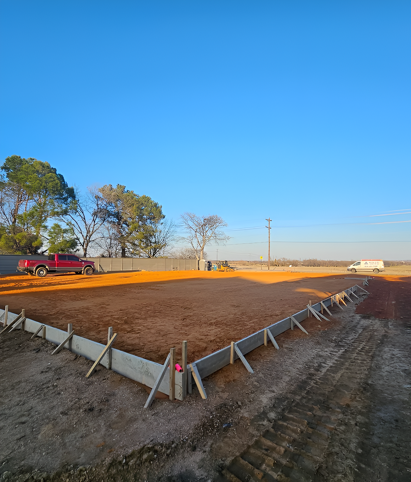Woman in straw hat smiles, holding wine glass near a lake.