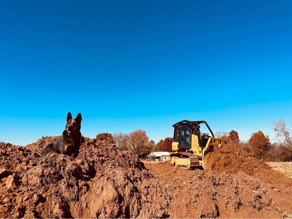Woman in straw hat smiles, holding wine glass near a lake.