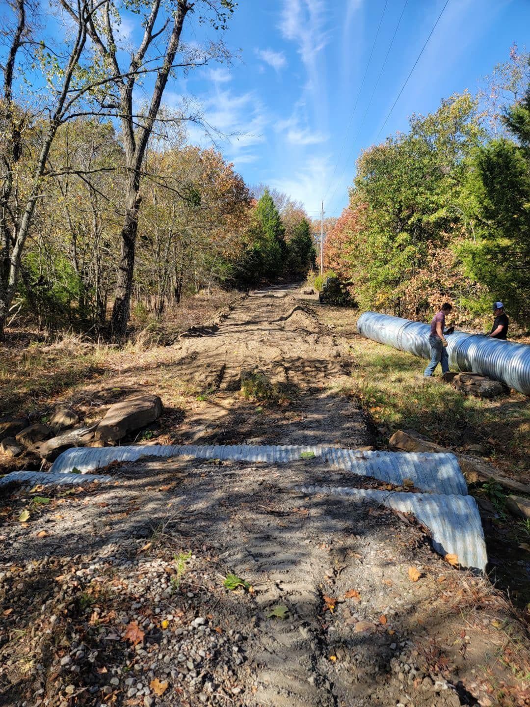 Woman in straw hat smiles, holding wine glass near a lake.
