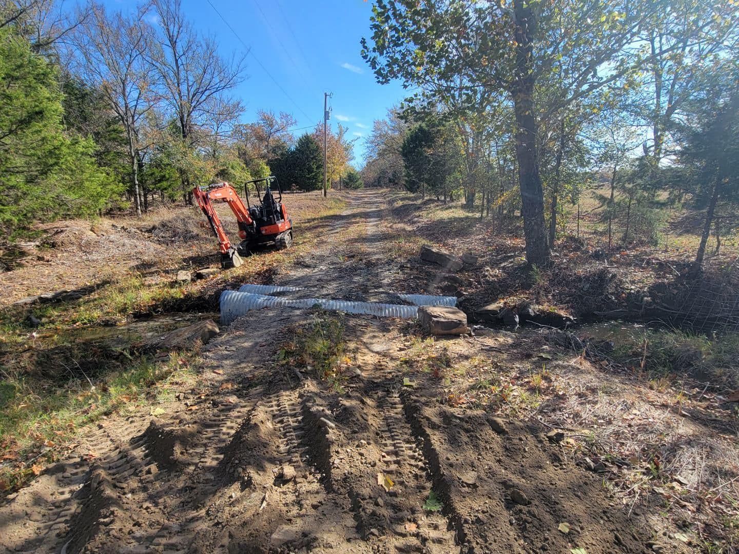 Woman in straw hat smiles, holding wine glass near a lake.