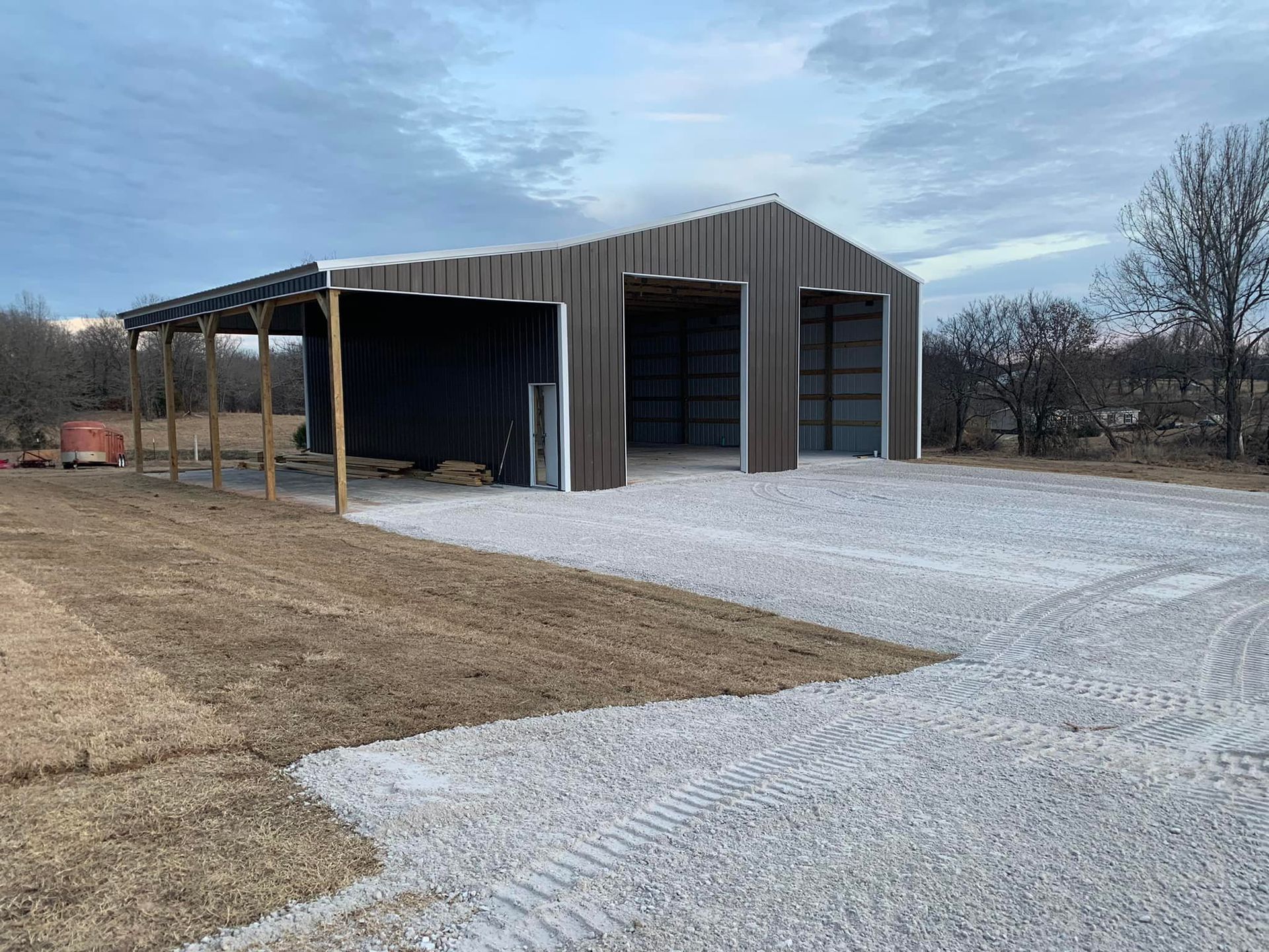 Woman in straw hat smiles, holding wine glass near a lake.