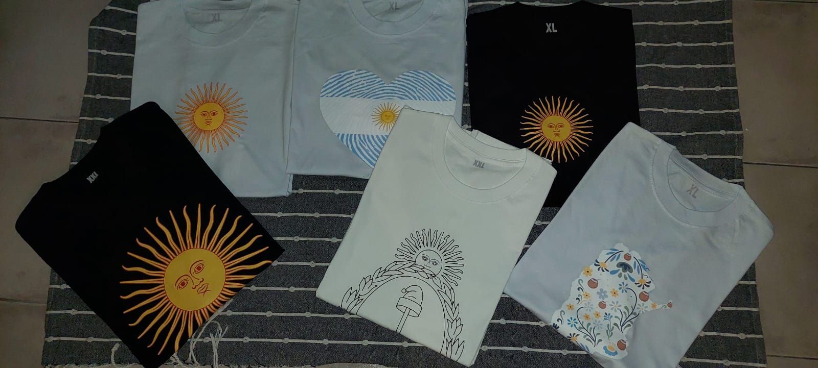 Varias camisetas con diseños estampados sobre un fondo oscuro tipo ladrillo.