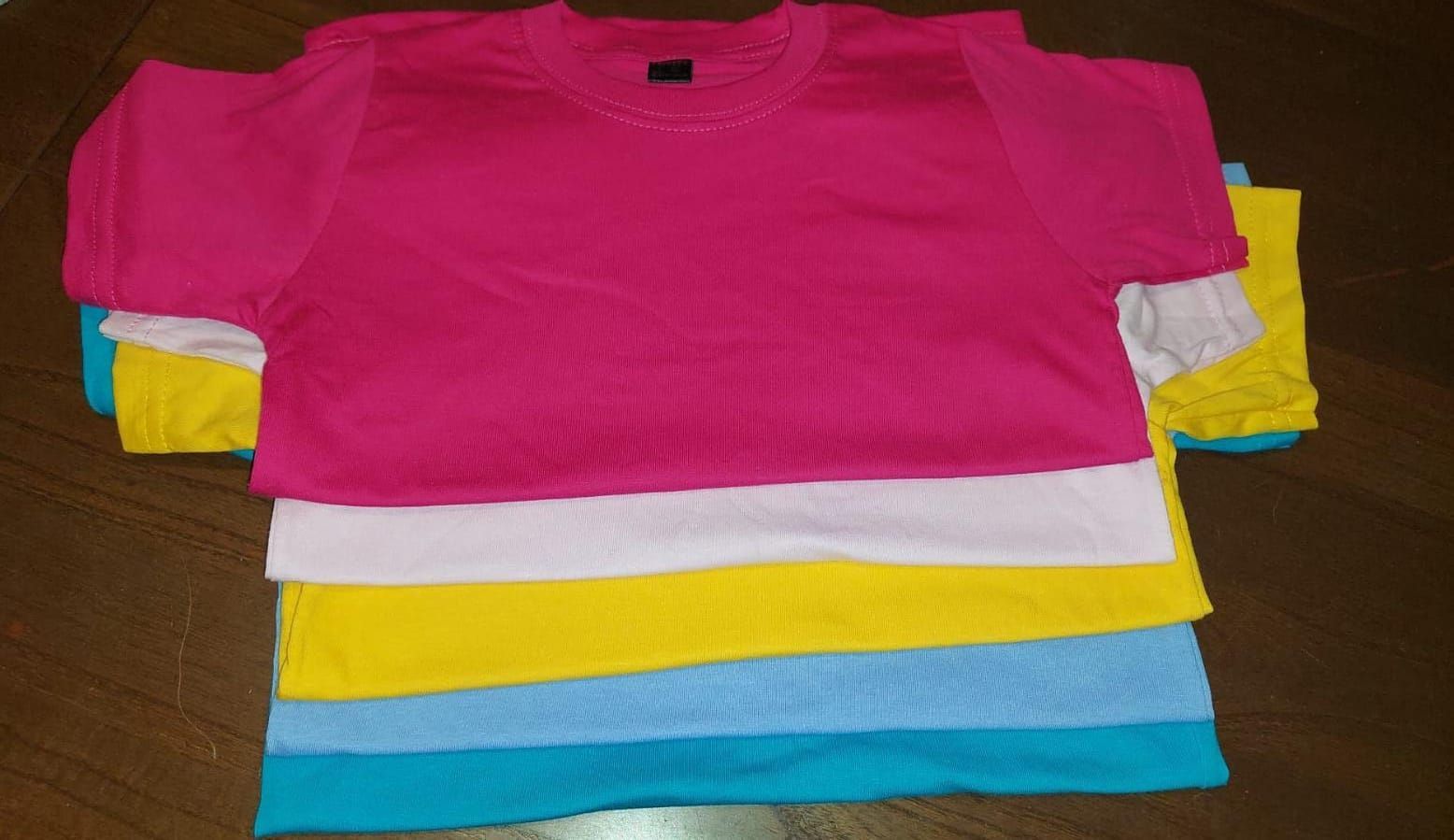Pila de camisetas dobladas en color rosa, blanco, amarillo y azul.