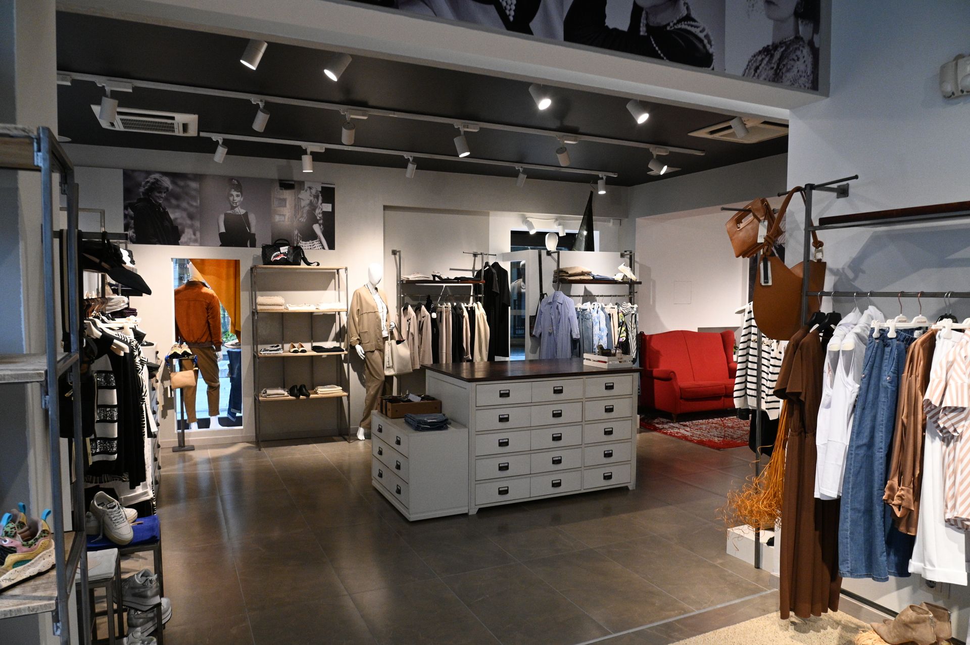 Un negozio pieno di vestiti e un divano rosso.