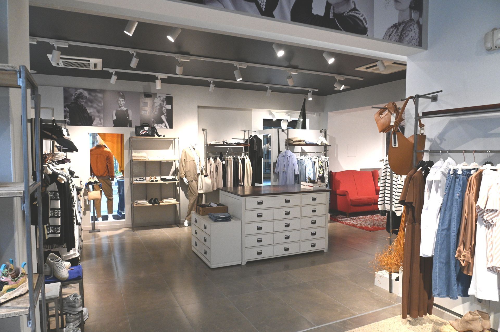 Un negozio pieno di vestiti e un divano rosso.