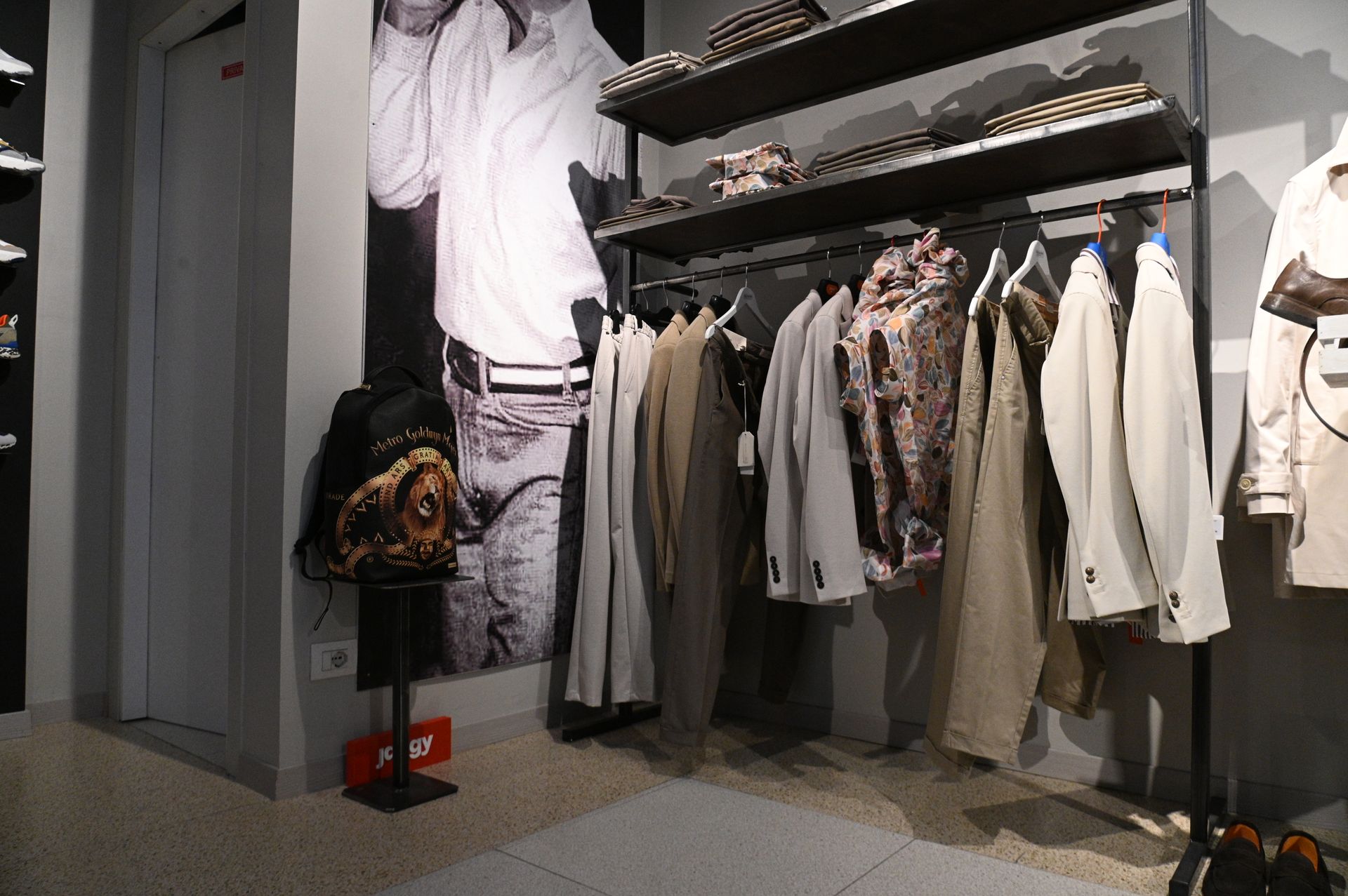 Interno di un negozio di abbigliamento con scaffali pieni di giacche e pantaloni e scaffali pieni di cappelli.