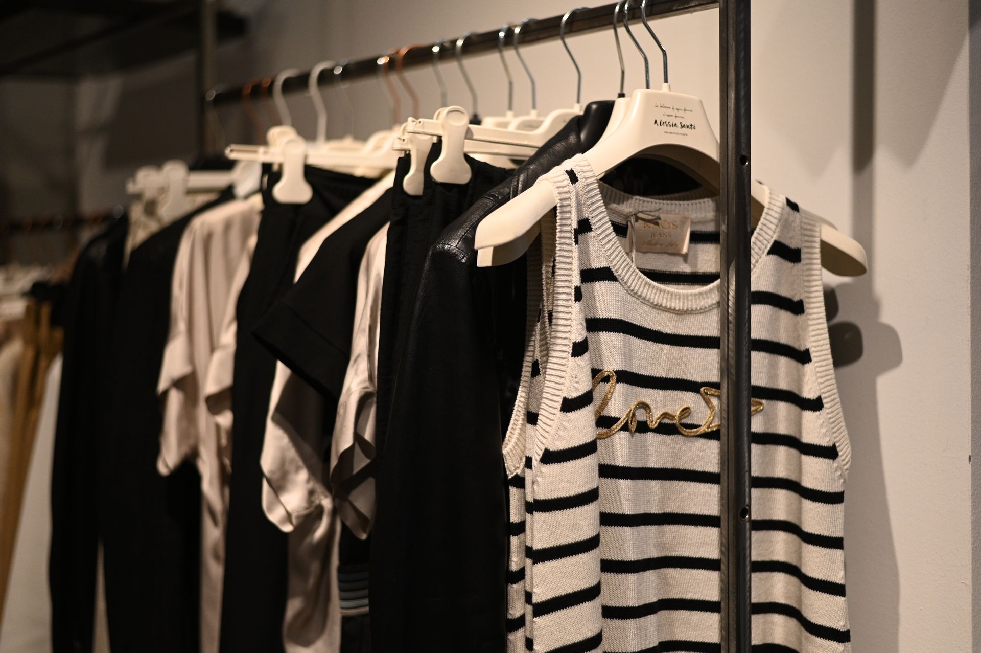 Vestiti appesi su uno scaffale all'interno di un negozio; in primo piano una canottiera a righe.