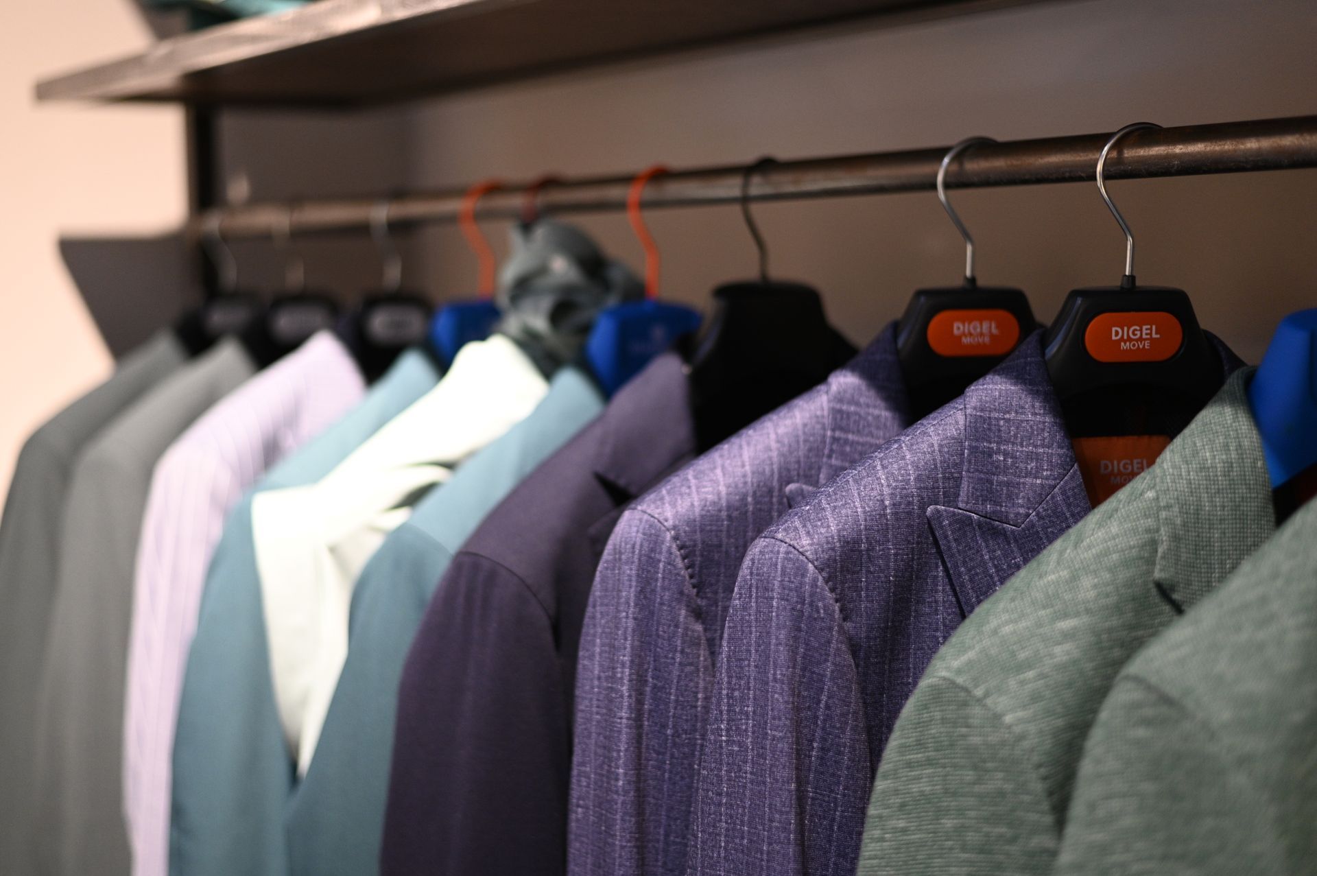 Fila di giacche colorate appese su uno scaffale in un negozio di abbigliamento.