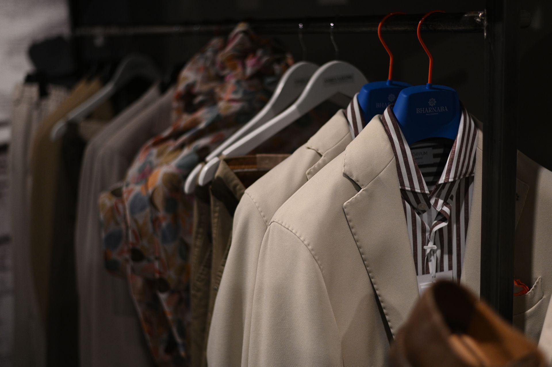 Appendiabiti con giacche e camicie in un negozio, toni neutri.